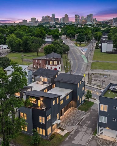 Rooftop terrace with fire pits and seating overlooking downtown city skyline at dusk